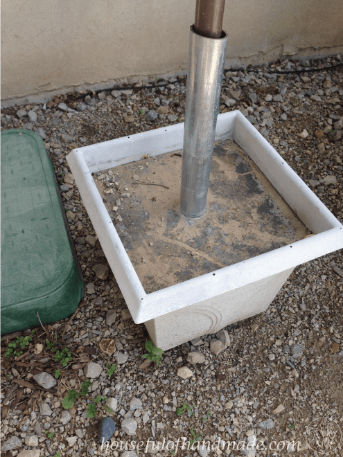 DIY umbrella stand shown in concrete planter while drying 