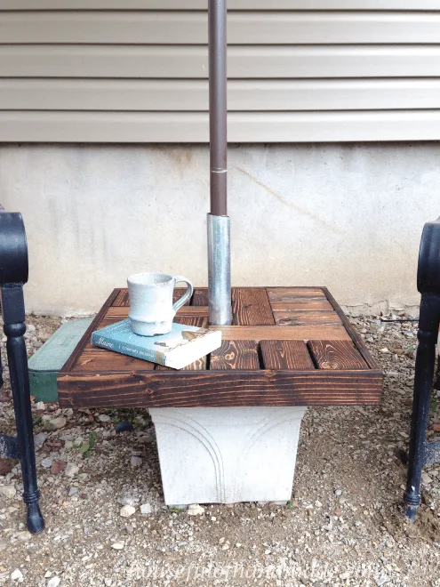 diy umbrella stand side table shown on patio with book on table and cup of coffee