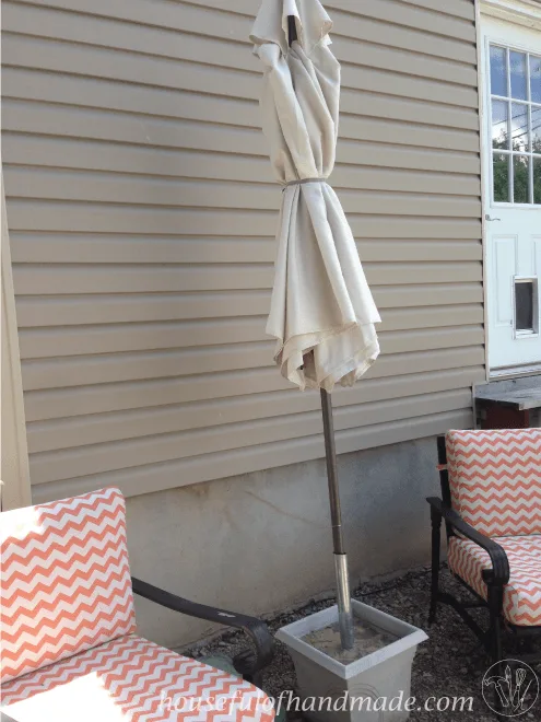 closed patio umbrella shown in DIY stand with two patio chairs 