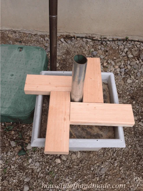 four pieces of wood shown on top of planter with base for DIY umbrella stand