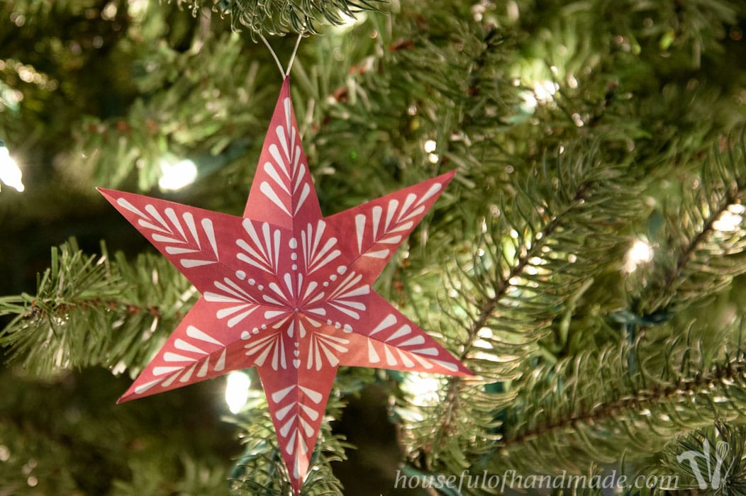 red and white 3d printable snowflake ornament in a lit christmas tree