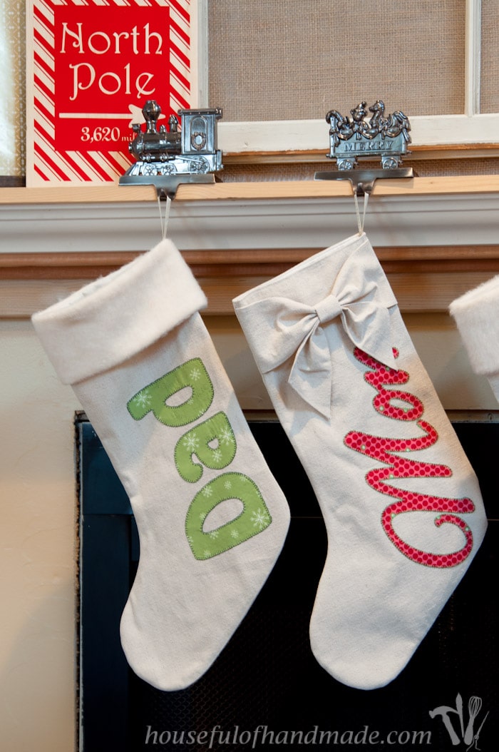 two DIY personalized drop cloth Christmas stockings hanging on fireplace mantel.