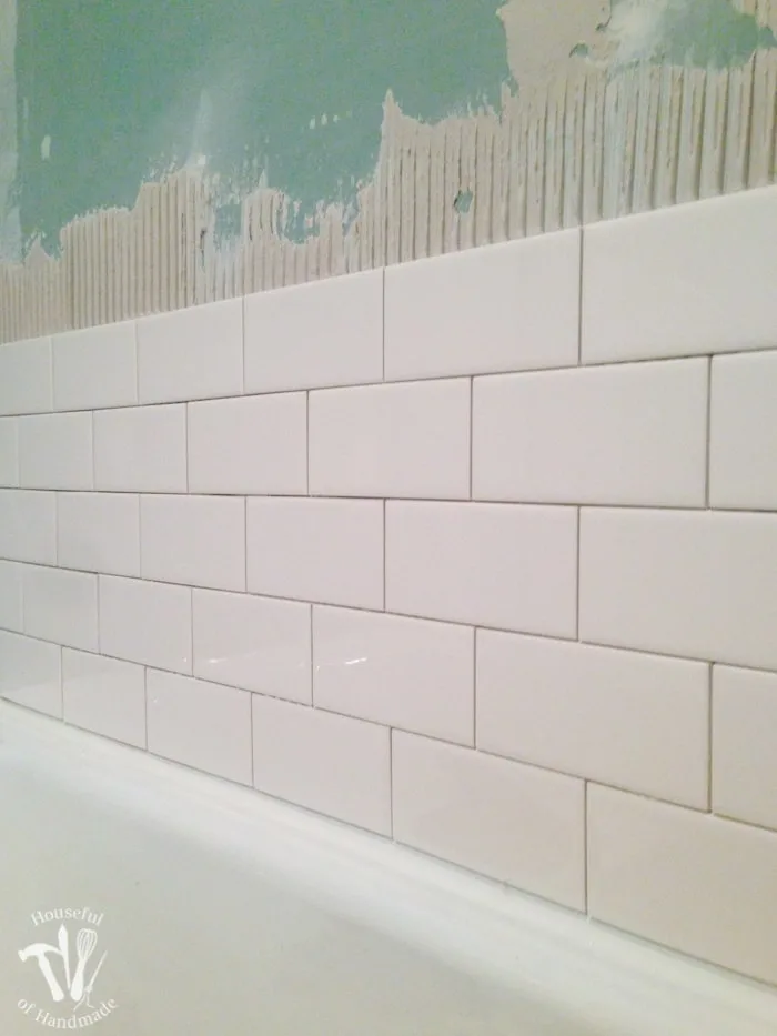 Bathtub surround being tiled with individual subway tiles.