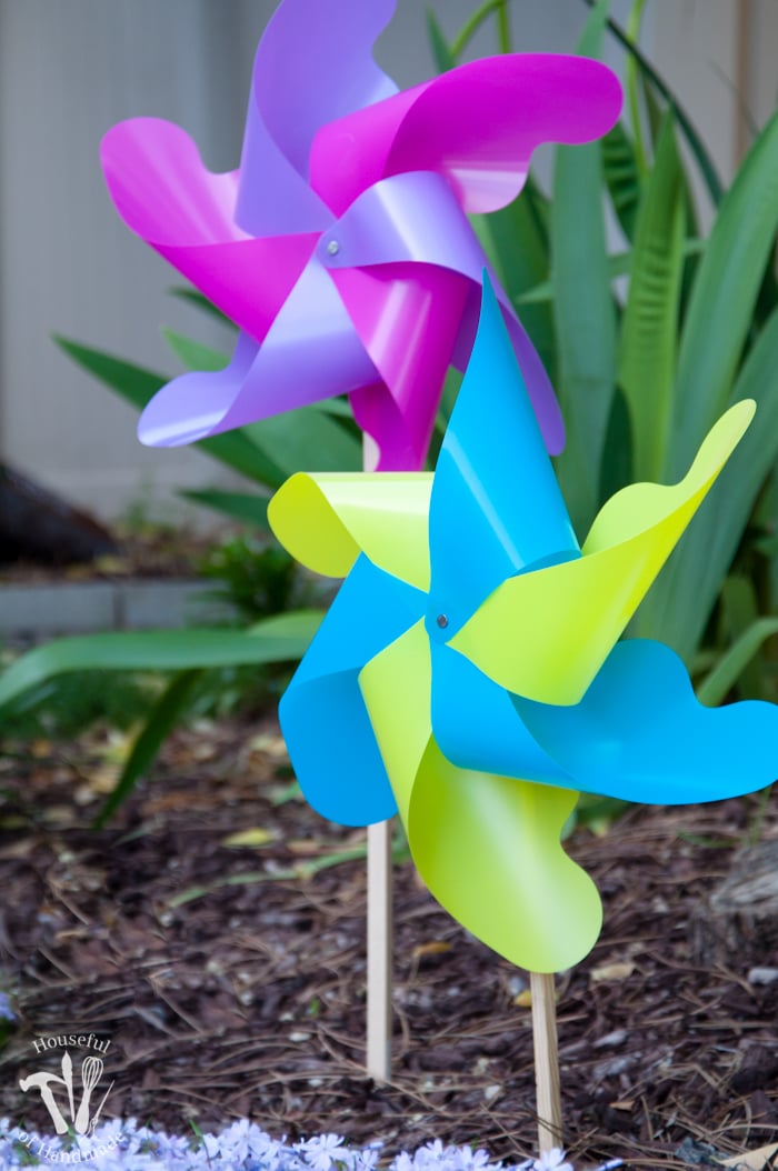 close up of finished pinwheels in garden. set of two pinwheels one in yellow and blue and one in pink and purple