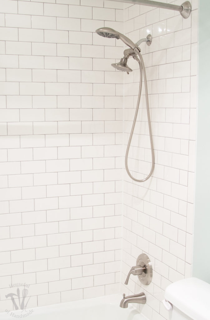 Shower around tub tiled with white subways tiles and a double shower head in brushed stainless steel. 