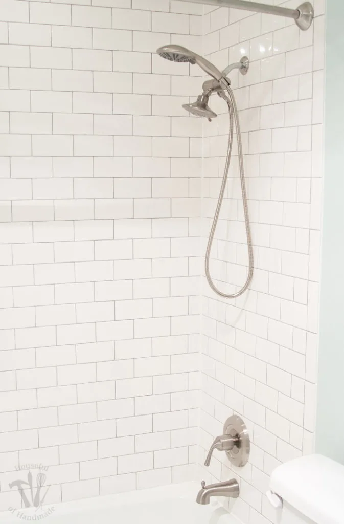 Shower around tub tiled with white subways tiles and a double shower head in brushed stainless steel. 