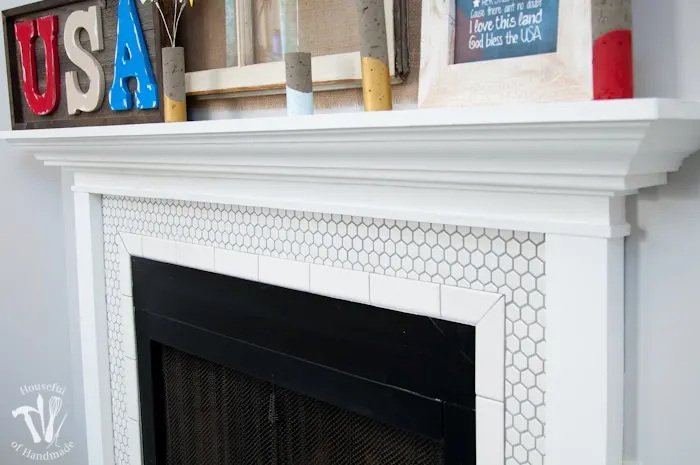 I love this vintage inspired farmhouse fireplace. DIY your own fireplace with new white hexagon tile on a budget. Love the white tiles and gray grout. Farmhouse fireplace reveal from Housefulofhandmade.com