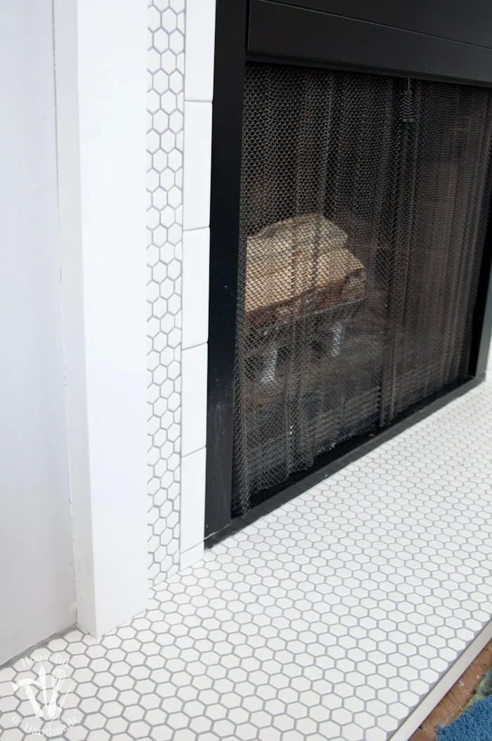 I love this vintage inspired farmhouse fireplace. DIY your own fireplace with new white hexagon tile on a budget. Love the white tiles and gray grout. Farmhouse fireplace reveal from Housefulofhandmade.com