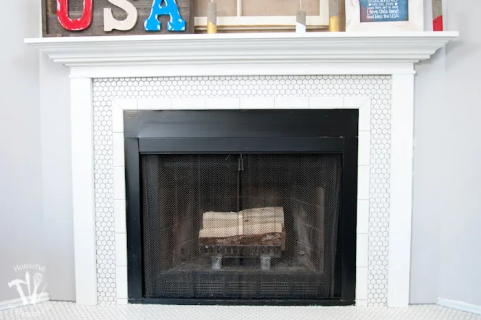 I love this vintage inspired farmhouse fireplace. DIY your own fireplace with new white hexagon tile on a budget. Love the white tiles and gray grout. Farmhouse fireplace reveal from Housefulofhandmade.com