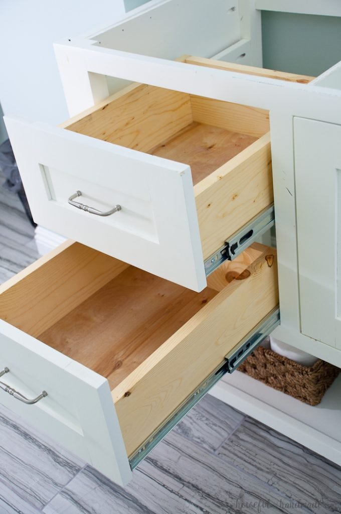 Two drawers in a white bathroom vanity open showing how deep they are inside. 