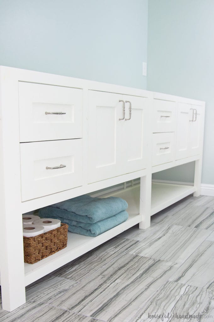 Double vanity with two sections of drawers and 2 cabinets with large open shelf below it.