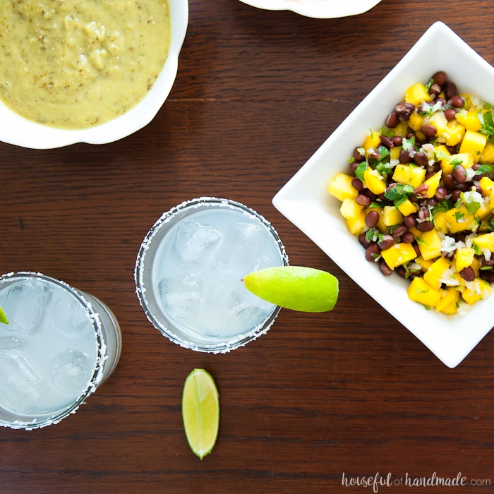 over head view of two margaritas, corn and bean salsa and tomatillo salsa for a Salsa & Margaritas Adult Birthday Party