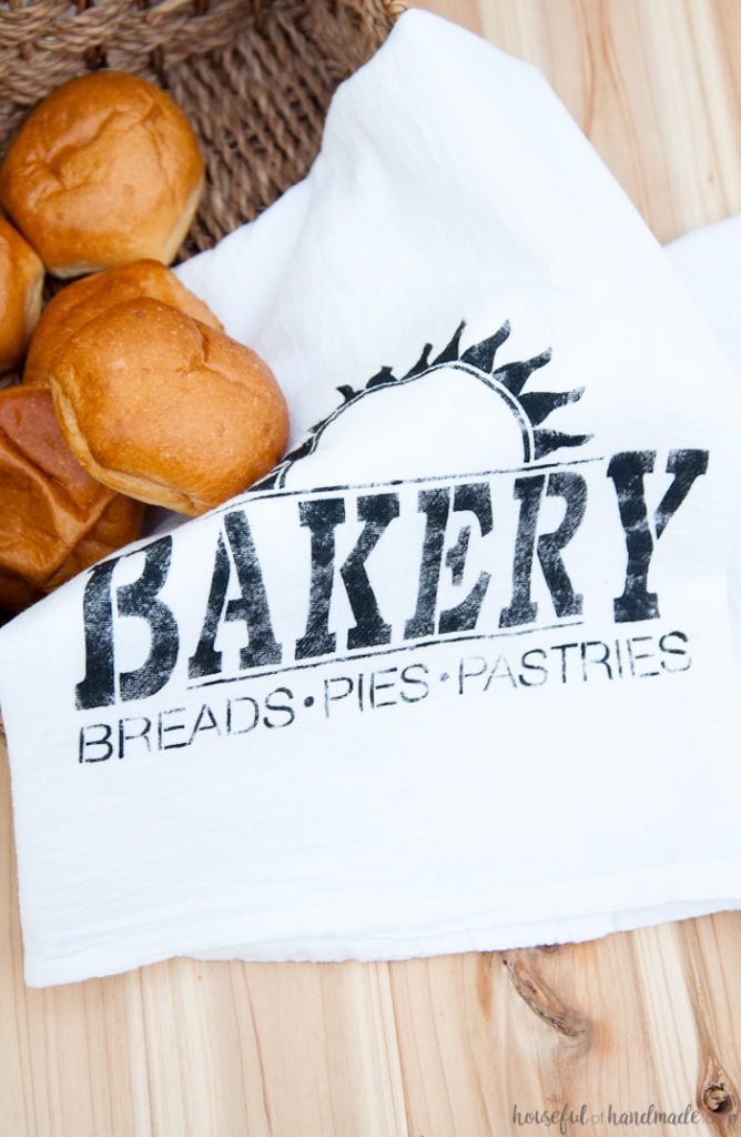 I want to make a bunch of these tea towels for gifts! These easy to make DIY bakery tea towels are a great way to add vintage charm to your kitchen or to give as gifts. Learn how to make a plastic stencil with your Silhouette to paint on inexpensive store bought flour sack towels. | Housefulofhandmade.com