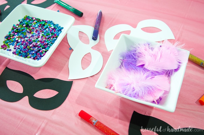 masquerade ball themed birthday mask decoration station with a bowl of jewels and feathers