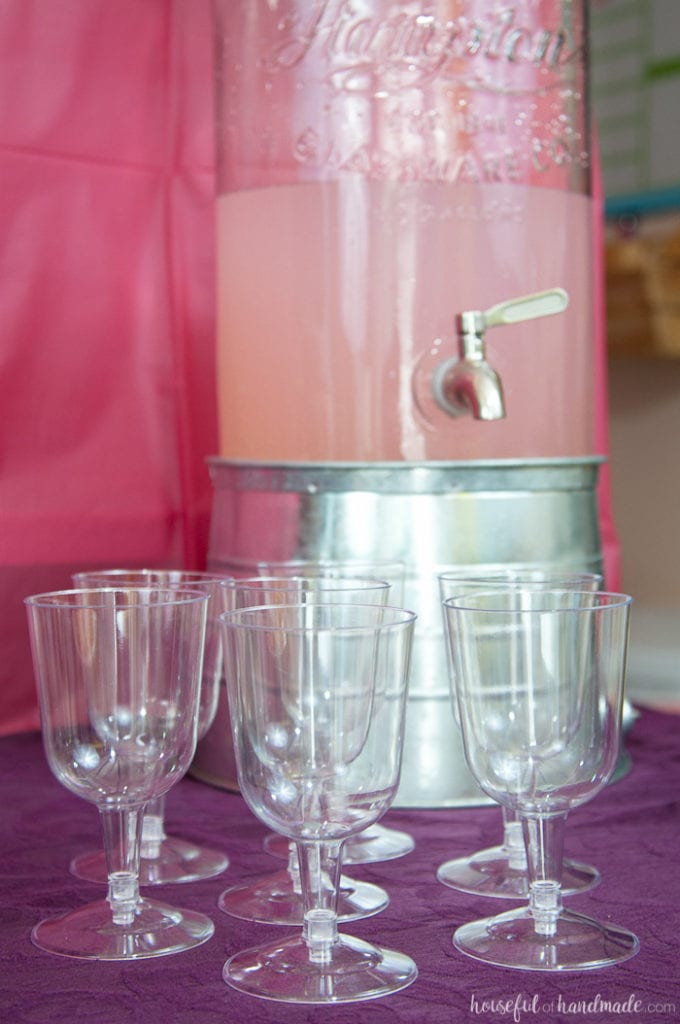 cups on a table in front of a pink lemonade mixed with lemon-lime soda for a masquerade ball themed birthday 