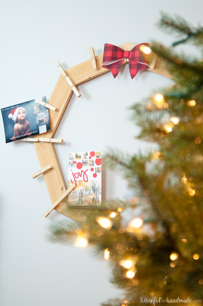 DIY wood Christmas card wreath shown on all behind tree with photo card