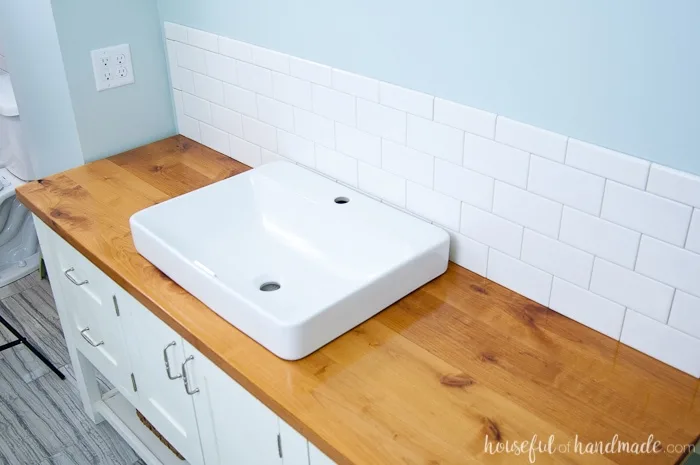 Looking down on the sealed wood bathroom countertop with a white vessel sink. 