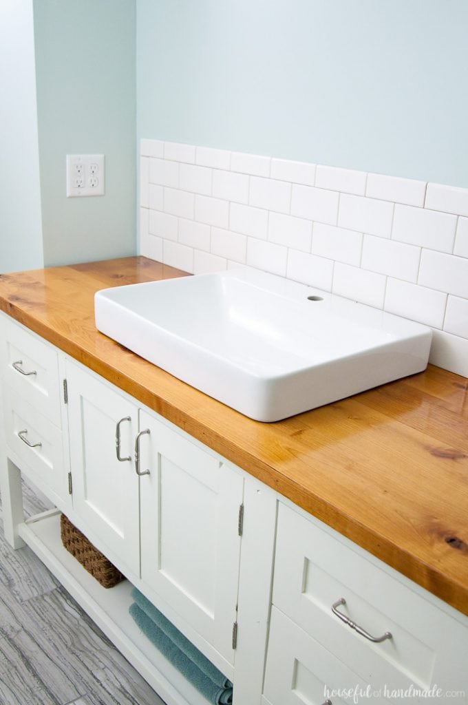 Spa like bathroom with white vanity and wood vanity top with white square vessel sink.