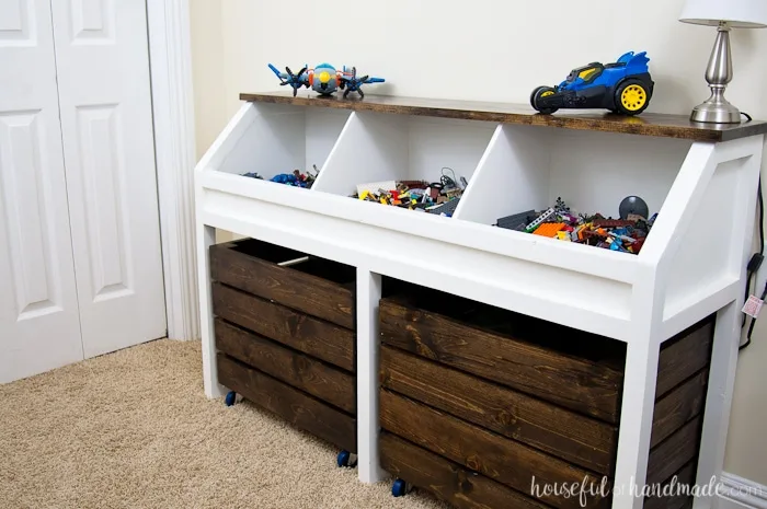 I love this grown-up take on a toy box! Create a console table to organize all the toys. This rustic toy storage unit has large open bins and rolling carts for lots of toy storage. Get the free build plans. | Housefulofhandmade.com