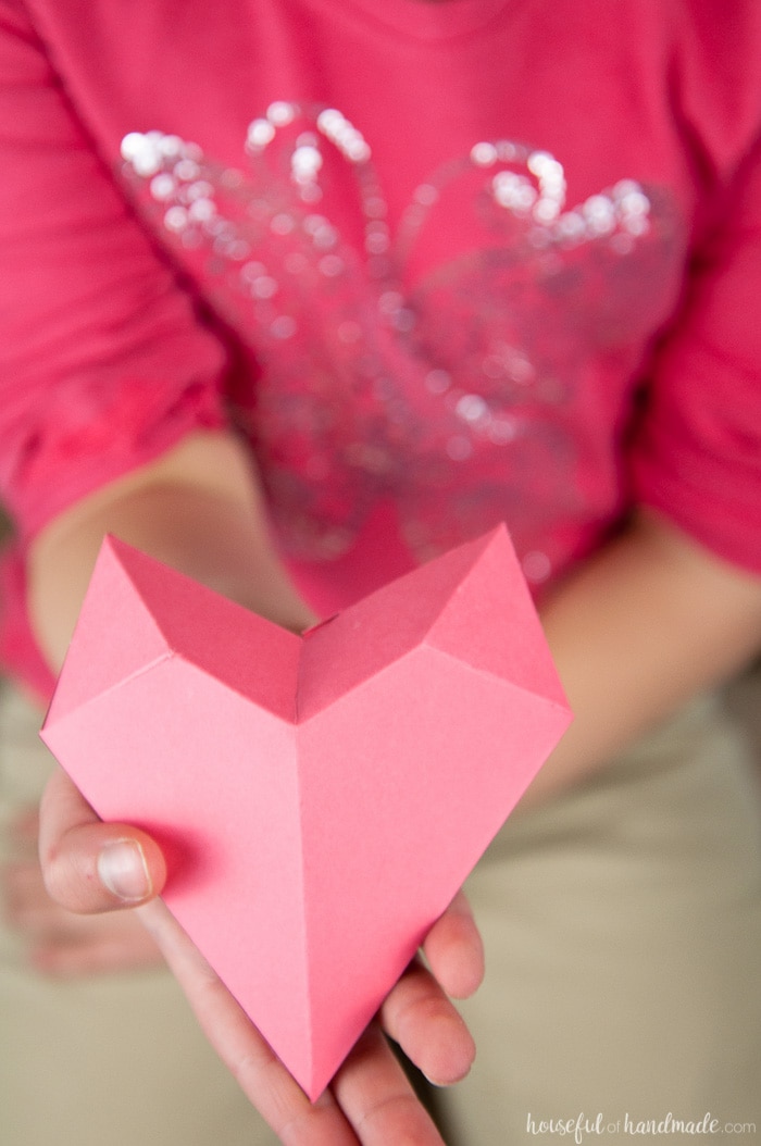 Child hand holding a pink DIY 3D heart valentine.