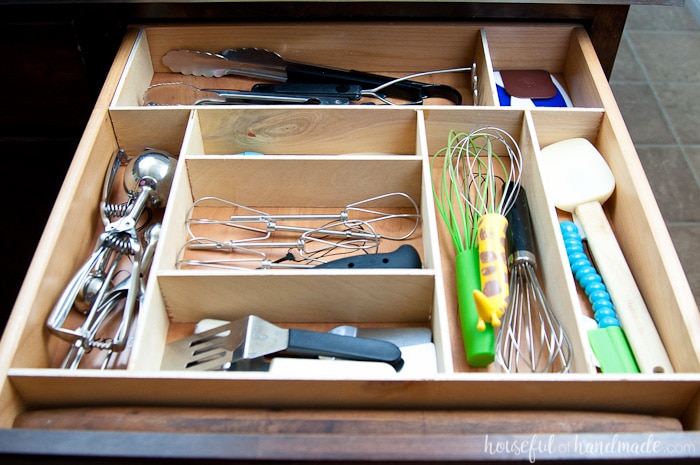 kitchen drawer with utensils organized with vinyl kitchen utensil drawings and wooden separators. 