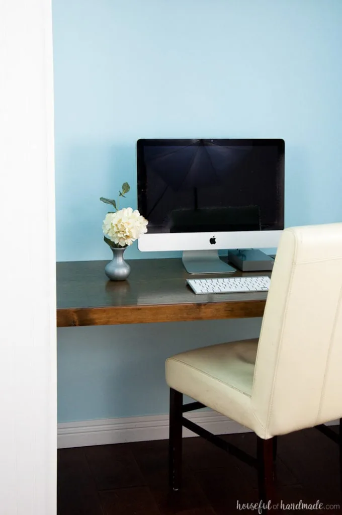 finished office in a closet shown with blue painted walls, wood stained desk top and office chair