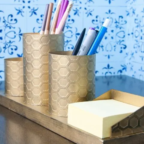 I love this painted brass DIY desk organizer to keep your favorite things organized on your desk. This organizer is made to look like brass with a beautiful chicken wire pattern, but you will never guess what it is actually made out of. Housefulofhandmade.com | Spellbinders | Embossing Plate | Brass Spray Paint | Paper Crafts | Desk Organization | Pencil Holder | Chic Desk Accessories | Farmhouse