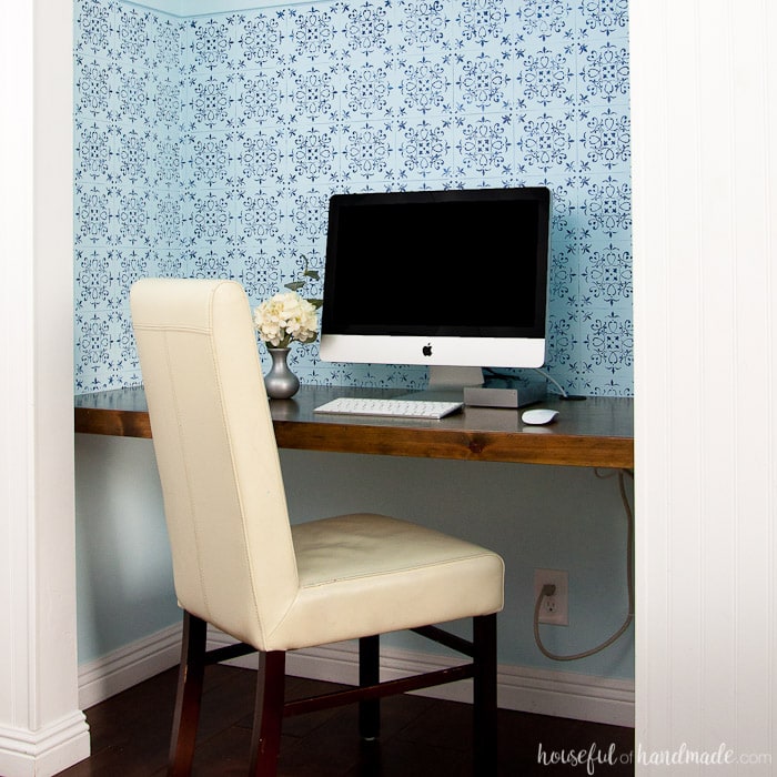 office in closet shown with wood desk, office chair, blue wall paper and office computer