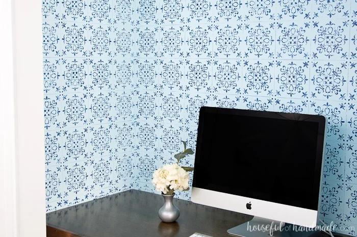 DIY desk shown in closet with blue pattern wall paper and white apple computer on wood desk 