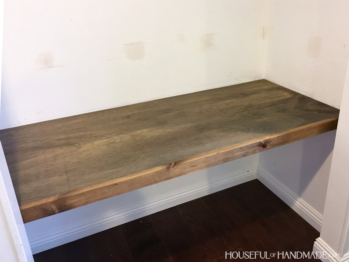 Dark stain wood desk top inside of office closet.