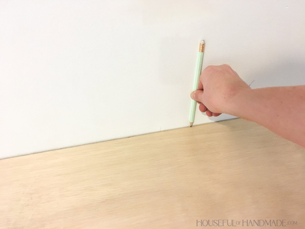 Wood desk top unstained with hand holding pencil to scribe the back wall.