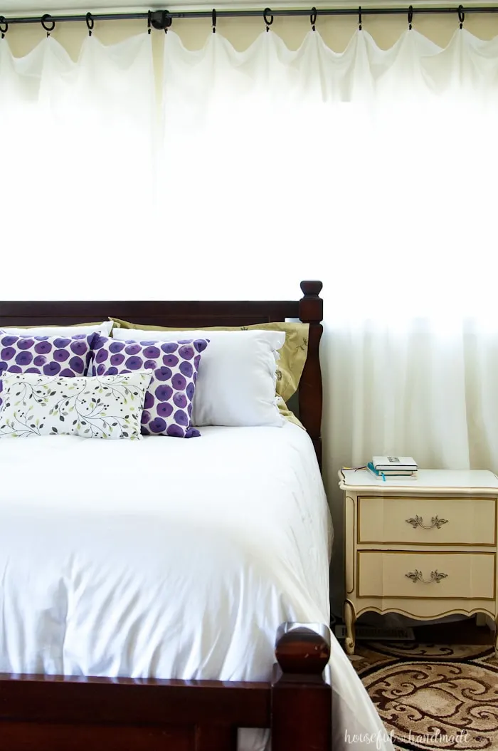 See how easy it is to complete a Master Bedroom Makeover in a weekend. A handful of simple projects can make your bedroom look bigger and brighter. Housefulofhandmade.com | Weekend Makeover | Bedroom Refresh | White Curtains | White bedding | Bed pillows | Bedroom Art | Roman Shades