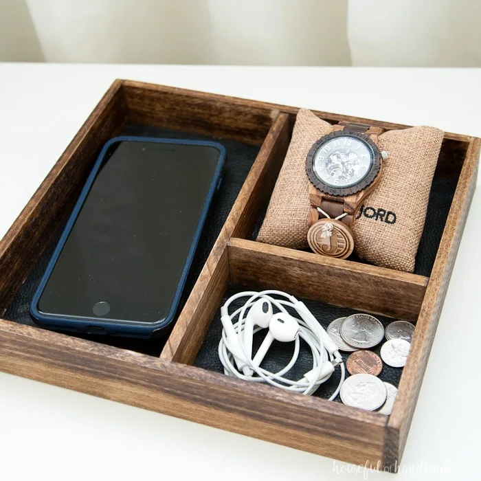 DIY nightstand tray holding an iPhone, earbuds, change and a watch. 