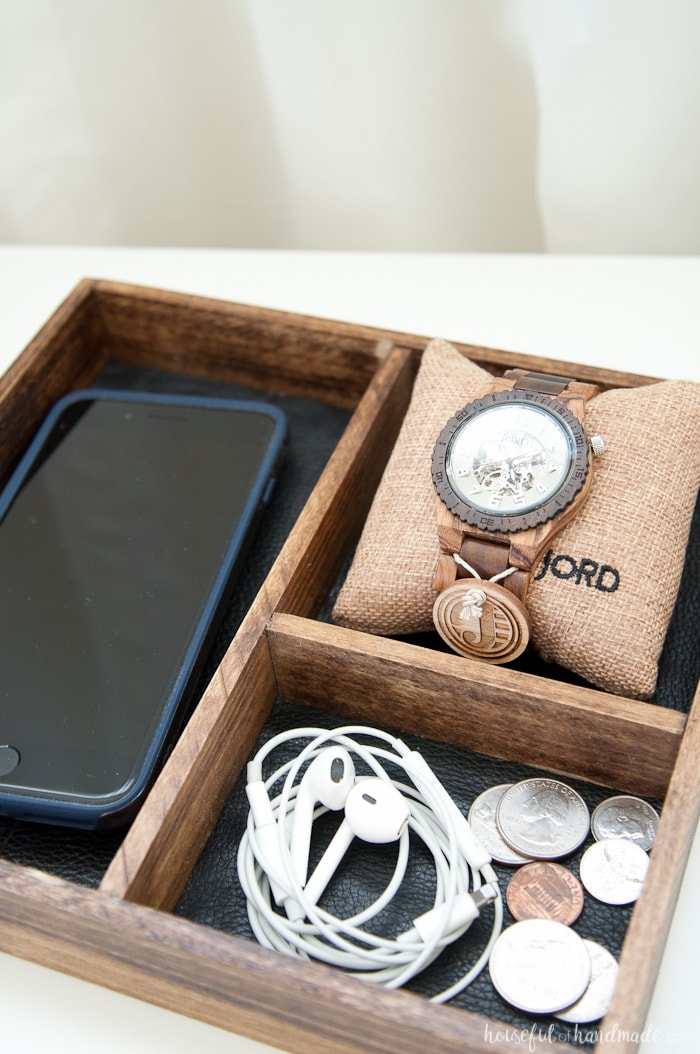 Close up of the DIY wood and leather nightstand tray holding items from the pockets. 