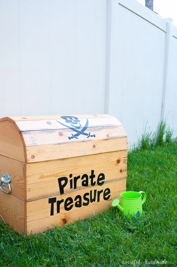 DIY treasure chest toy box shown outside with green watering can.