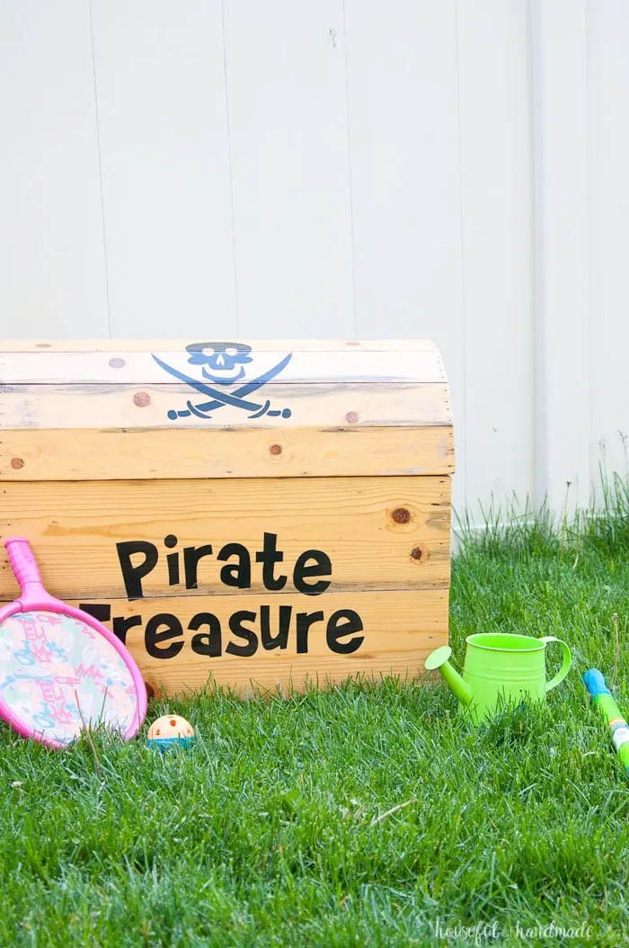 DIY treasure chest toy box shown on grass with kids toys.