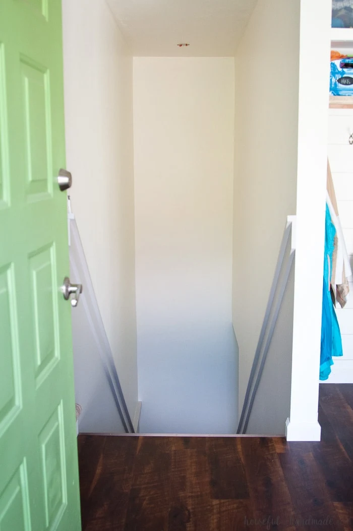 image of painted staircase with green door and hardwood floors