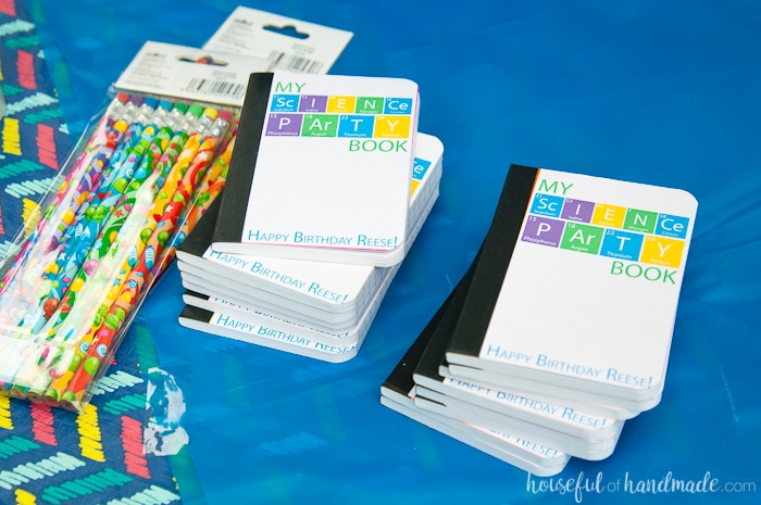 custom science themed notebooks for a kids birthday party on a table next to a pack of science pencils
