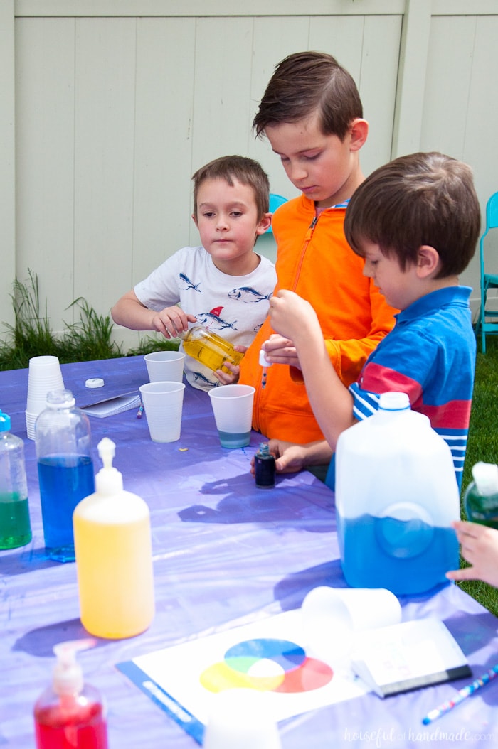 young kids doing experiments with colored water at a science themed birthday party