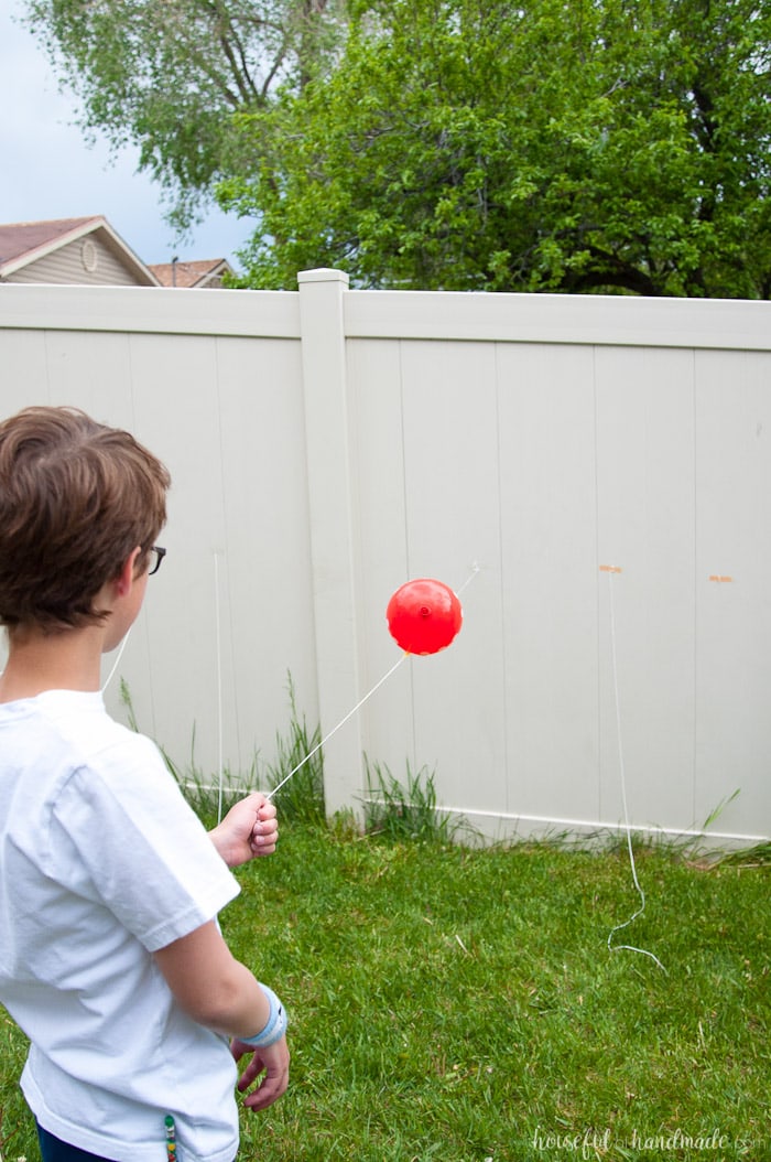 young boy playing balloon racer game at science themed birthday party