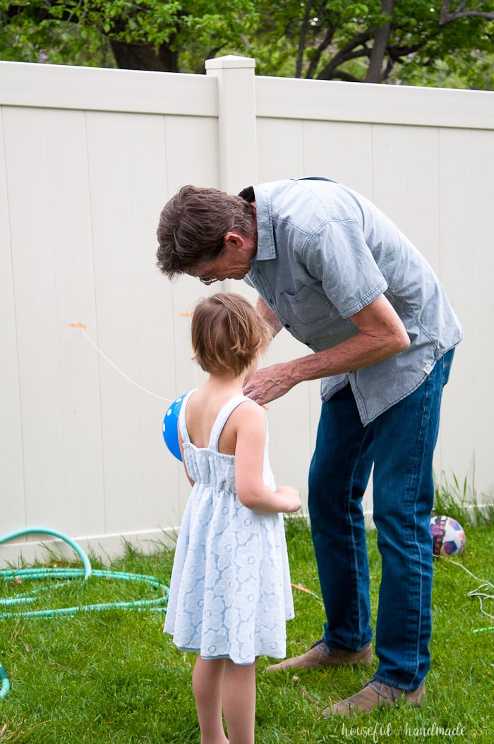 young girl and her grandfather setting up balloon racer game for science themed birthday party