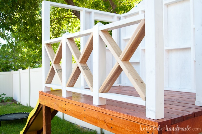 Our DIY Playhouse is coming along! This week we tackled the playhouse railing. The beautiful X railing is perfect for the cute cottage playhouse. See how we are building the playhouse step-by-step including free build plans and time/cost breakdown. Housefulofhandmade.com | DIY Playhouse | Playhouse Build Plans | DIY Swing Set | How to Build a Playhouse | DIY Sandbox | How to Build an X Railing