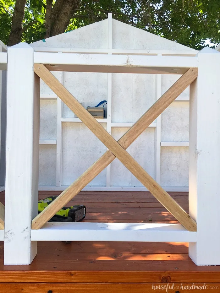 Our DIY Playhouse is coming along! This week we tackled the railing. The beautiful X railing is perfect for the cute cottage playhouse. See how we are building the playhouse step-by-step including free build plans and time/cost breakdown. Housefulofhandmade.com | DIY Playhouse | Playhouse Build Plans | DIY Swing Set | How to Build a Playhouse | DIY Sandbox
