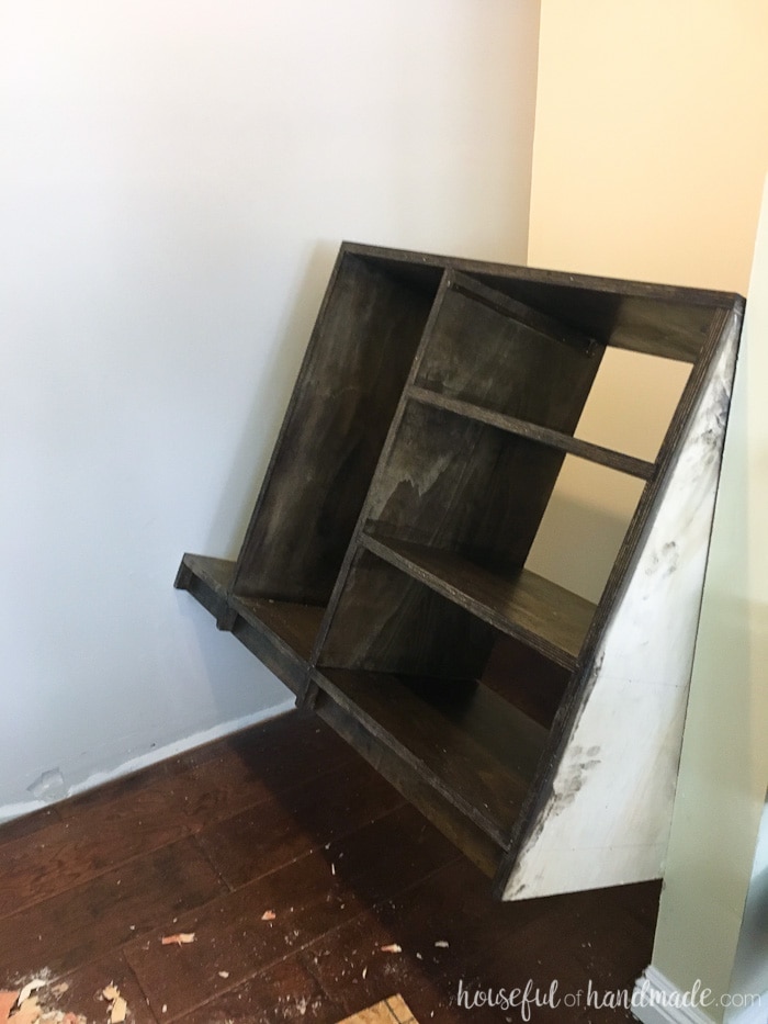 Plywood closet shelves being shimmied into the closet. 