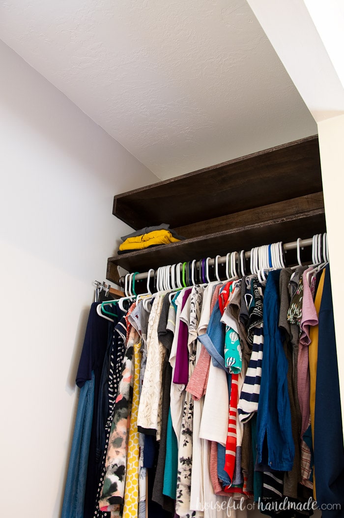 Completed closet with a hang bar attached to the shelf supports and clothes hanging on it.