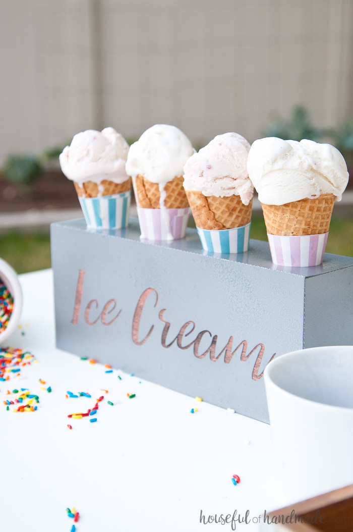 DIY farmhouse ice cream cone holder on a table with sprinkles spilled and dripping ice cream cones