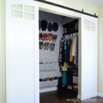 Small master closet with white barn doors open showing the DIY closet organization system.