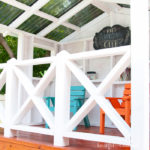 Close up view of the white x-railing in the kids playhouse with blue and orange chairs in the background.