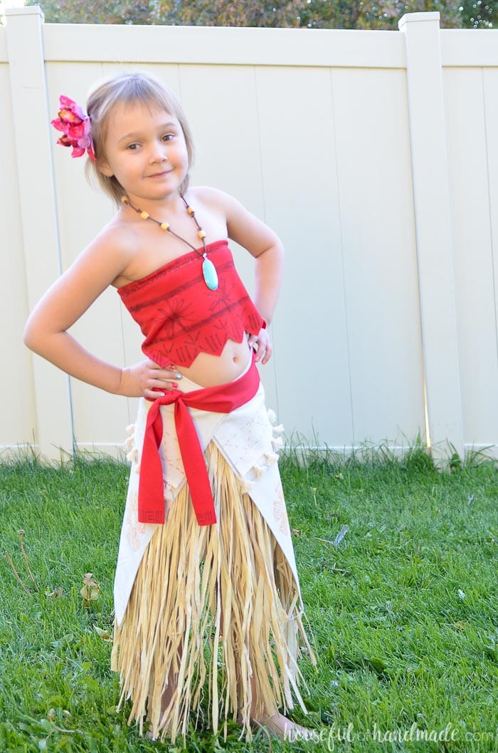 DIY Moana costume with red top and beige grass skirt shown on little girl outside. 