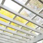 Looking up through a white painted pergola through the clear pergola roof.